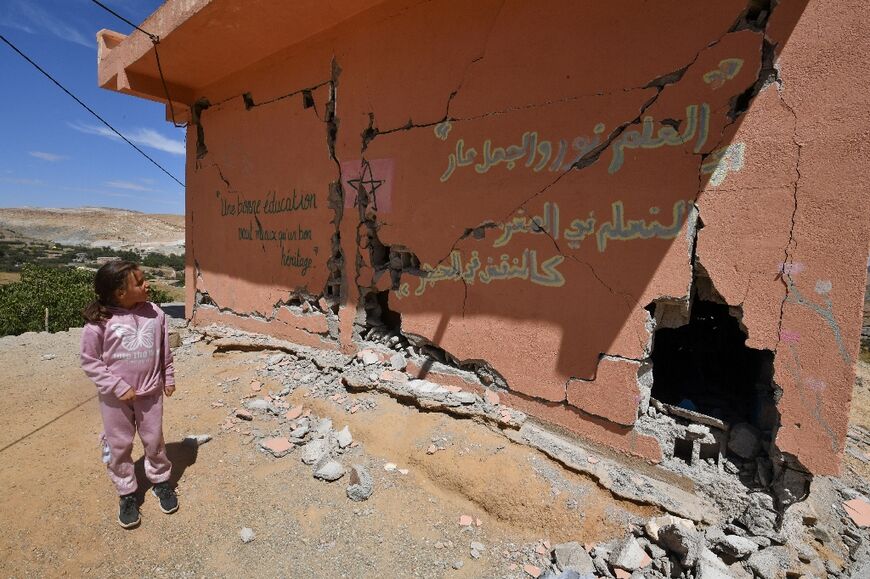 A girl stands outside a heavily damaged school in the earthquake-hit village of Ardouz, in Morocco's Amizmiz region 