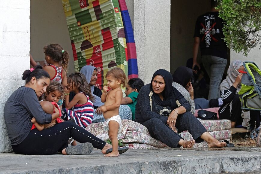 Women sit with their children after fleeing the fighting at Ain al-Helweh