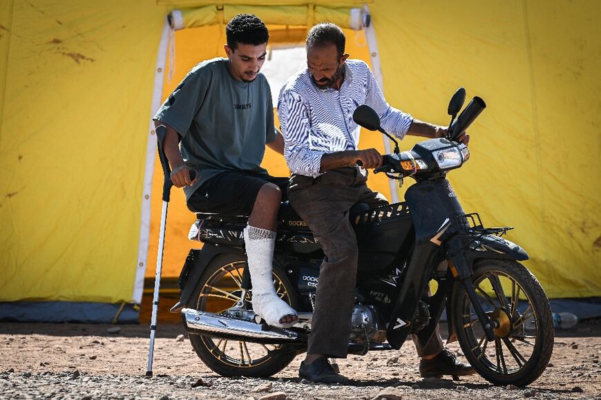 A man transports a survivor of the quake whose leg was injured, as they leave a military field hospital in the village of Asni near Moulay Brahim in al-Haouz province 