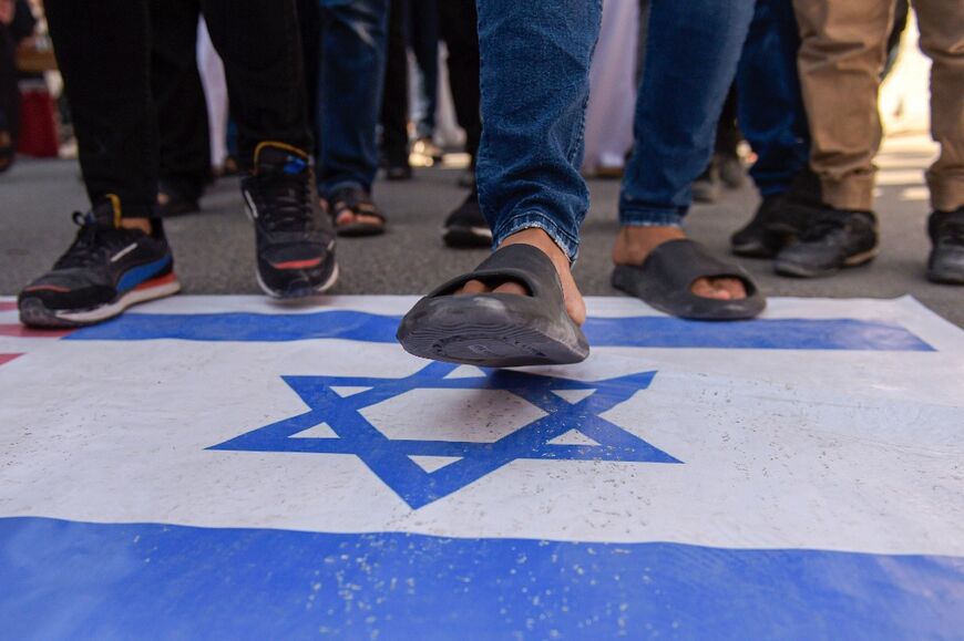 A protester walks on a depiction of the Israeli flag in Manama, Bahrain