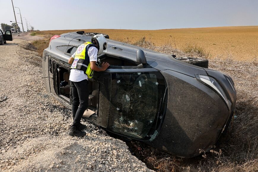 A member of the Magen David Adom emergency medical services checks a bullet-riddled car near Sderot