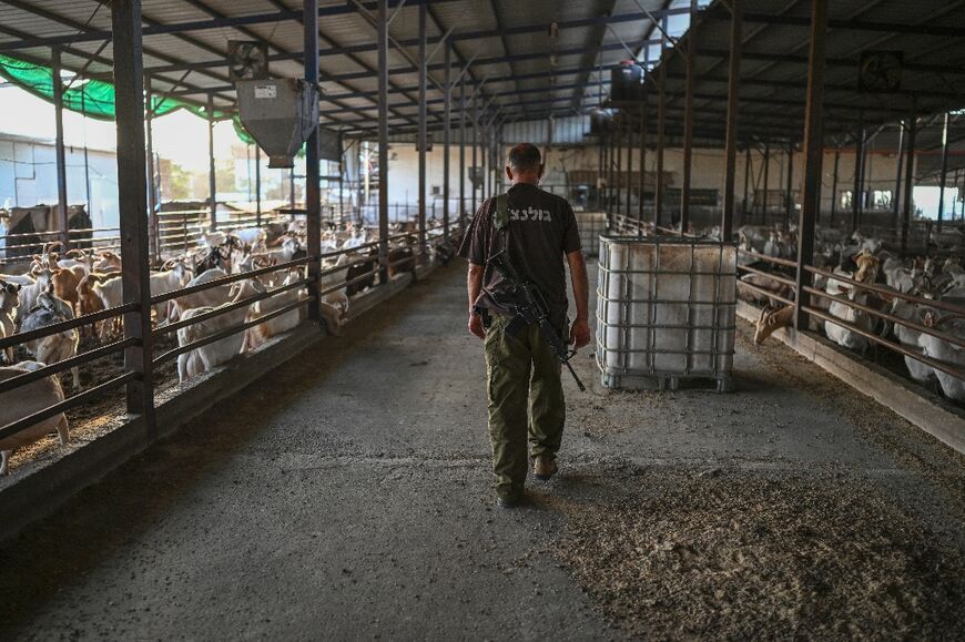 Israeli farmer Doron Dadoush walks, armed with an asault  rifle, through a goat pen at a farm in Goren village near the northern border with Lebanon 
