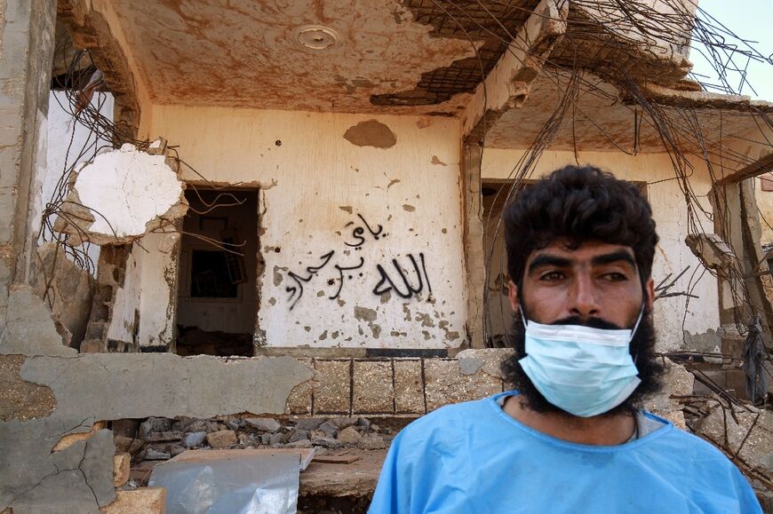 A medical worker in front of a building destroyed in the September 10-11 flash floods in Derna 