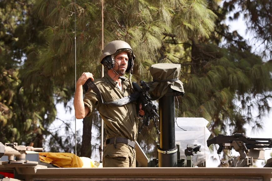 An Israeli soldier stand in an armoured vehicle stationed at an undisclosed area in northern Israel near the Lebanon border on October 23, 2023