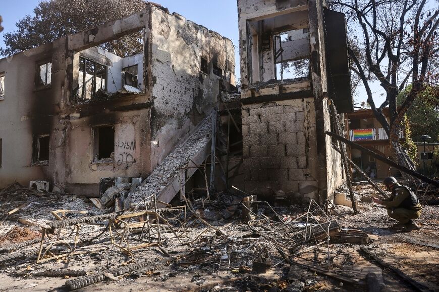 An Israeli officer inspects a burnt house on October 17, 2023 in Kibbutz Beeri near the border with Gaza