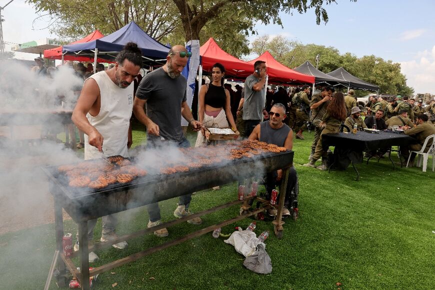 Israeli civilian volunteers feed soldiers at a barbeque and check their wellbeing prior to their deployment to the zone along the Israeli-Gaza border near Ofakim