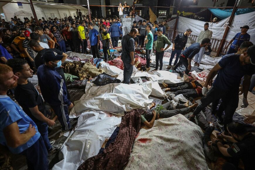 People gather around bodies of Palestinians killed in a strike on the Ahli Arab hospital in central Gaza after they were transported to Al-Shifa hospital, on October 17, 2023. 