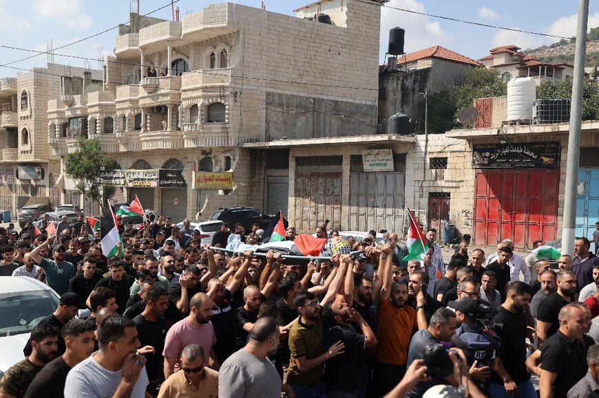Palestinians carry the body of 19-year-old Labib Damidi, who was shot dead overnight in Huwara