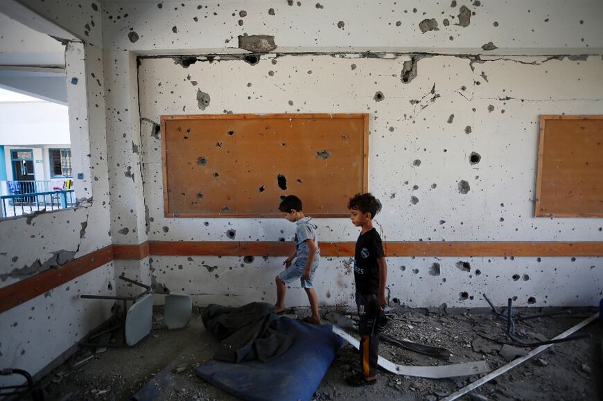 Young boys stand in a shrapnel-pocked room inside a UN-run school in the  Al-Maghazi refugee camp in central Gaza Strip
