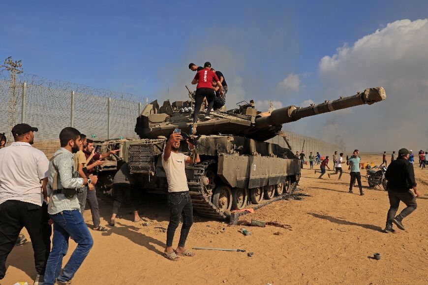 Palestinians take control of an Israeli tank after crossing the border fence with Israel from Khan Yunis in the southern Gaza Strip on October 7, 2023