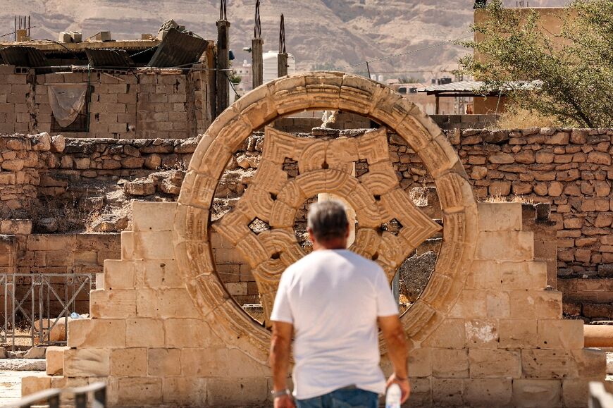 A tourist stands before a stone rosette at Hisham's Palace, an Islamic archaeological site lying north of Jericho