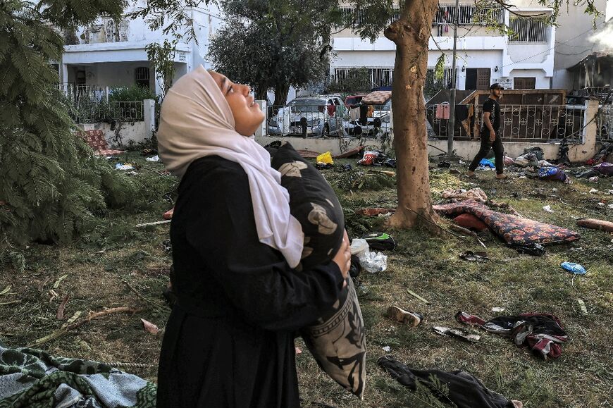 A woman stands amid debris outside the site of the Ahli Arab hospital in central Gaza on October 18, 2023 in the aftermath of an overnight strike there