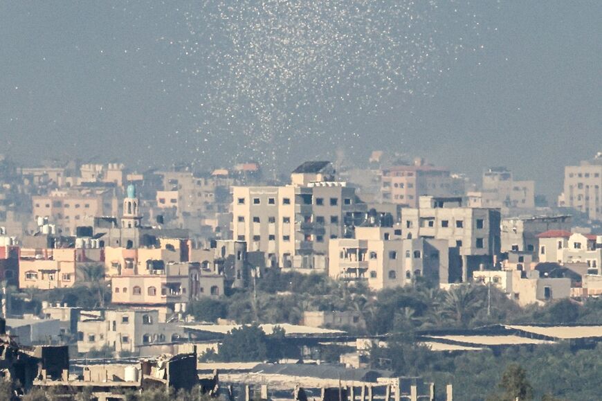 A picture taken from the border between Israel and Gaza shows leaflets dropped by the Israeli army over Gaza City, telling people to move to the south of the Palestinian territory