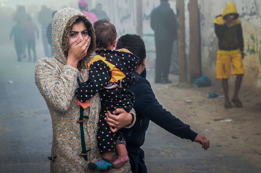 A woman holding a child flees following an Israeli strike in Rafah