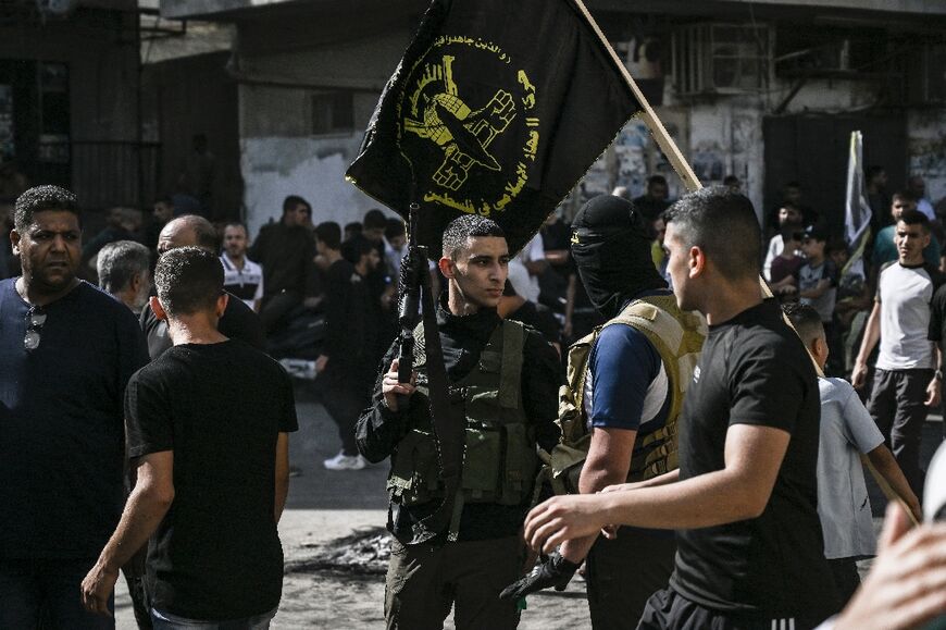 Children carry the black and yellow flag of militant group Islamic Jihad as its fighters parade their weapons