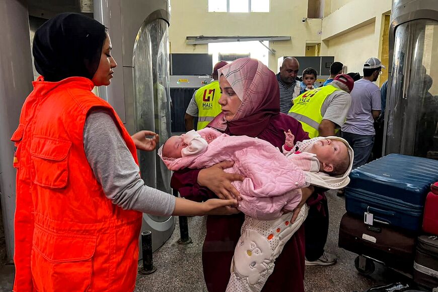 A woman walks with two infants after crossing on the Egyptian side of the Rafah border crossing with the Gaza Strip