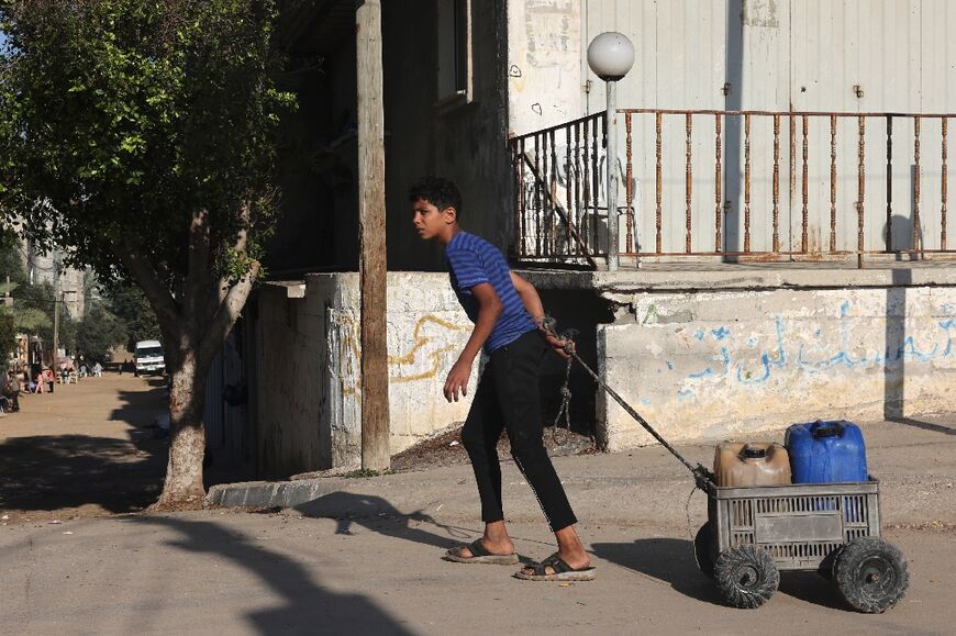A Palestinian transports a jerrycan filled with clean water in Rafah