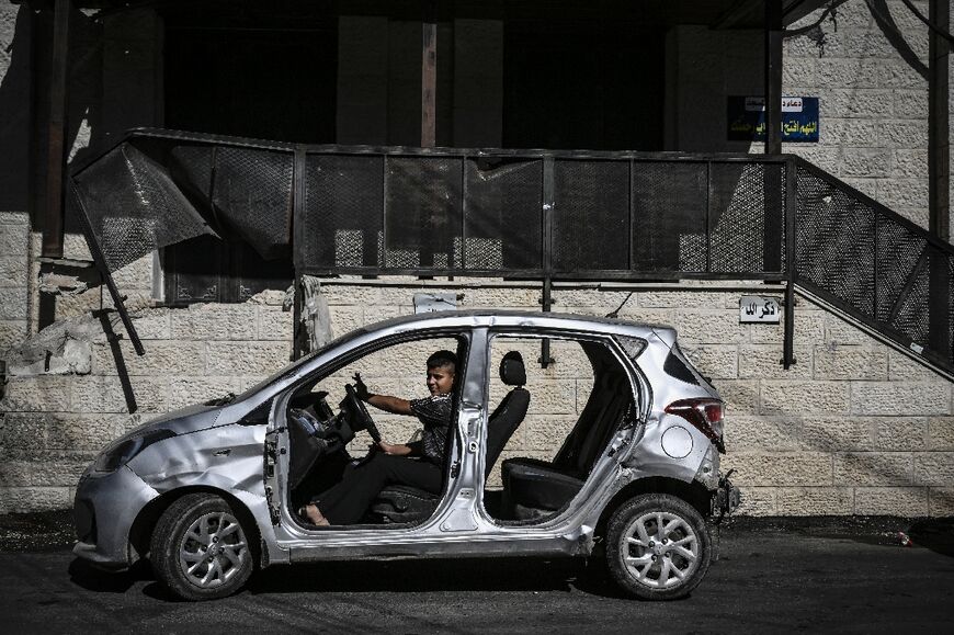 A young Palestinian boy plays a damaged car