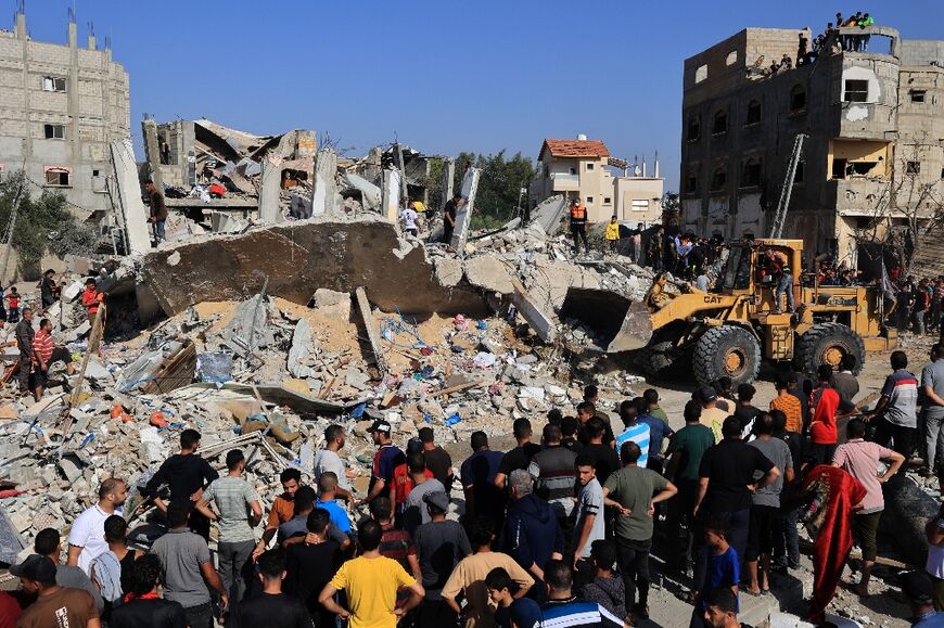 Palestinians rescuers look for survivors as others watch a digger remove concrete blocks after an Israeli strike on Rafah