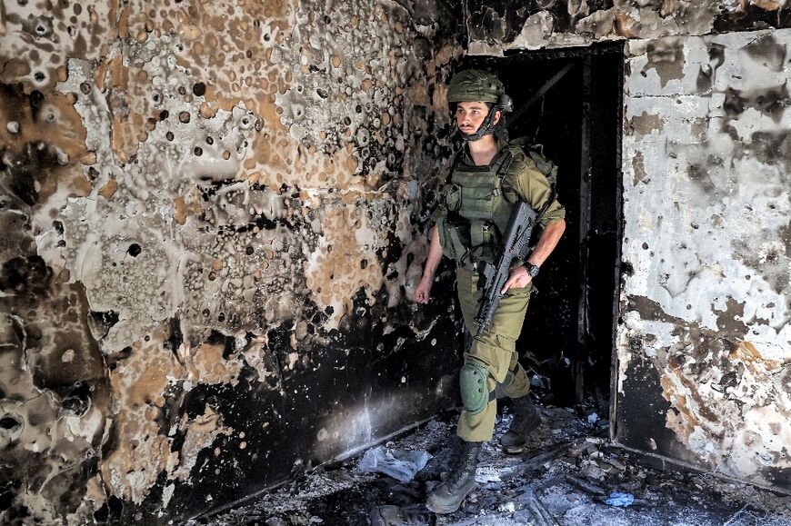 An Israeli soldier walks through a burnt building in Kfar Aza, over a week after the Hamas attack