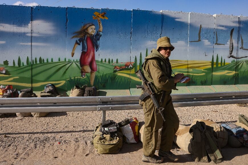 An Israeli soldier stands in front of a mural near kibbutz Nahal Oz on the border with the Gaza Strip on October 15, 2023