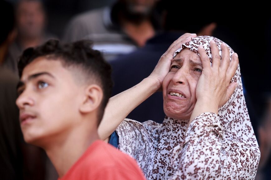 A Palestinian woman looks on with horror at the aftermath of an Israeli strike on Gaza's Nuseirat refugee camp