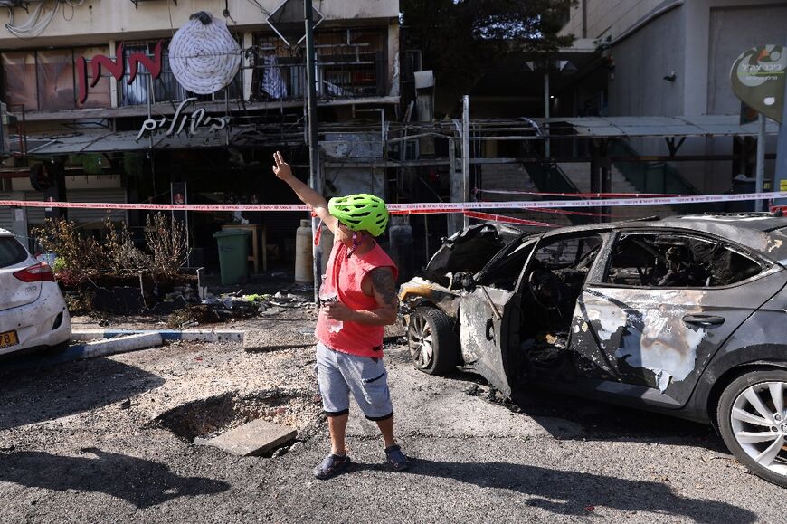 A man  gestures towards the damage from the rocket attack on Kiryat Shmona