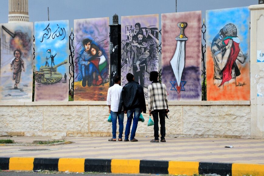 Yemeni men look at graffiti in solidarity with the Palestinians of the Gaza Strip and the West Bank painted on the wall of a mosque in Sabeen Square in Sanaa on November 20, 2023