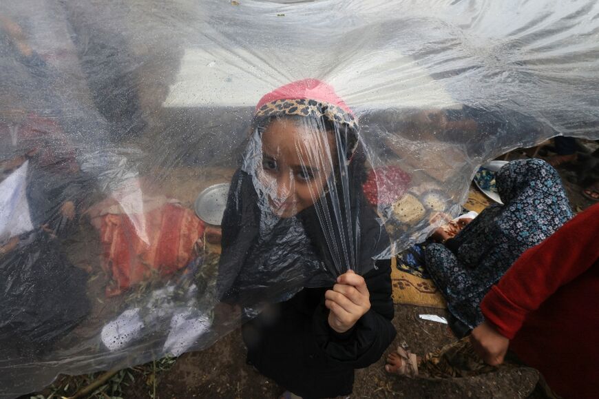 A Palestinian girl stands inside a tent amid the rain at camp for displaced people in Rafah, in the southern Gaza Strip