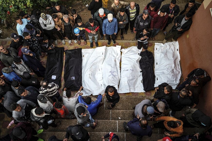 People stand over the shrouded bodies of loved ones killed during Israeli bombardment, at Nasser hospital in Khan Yunis