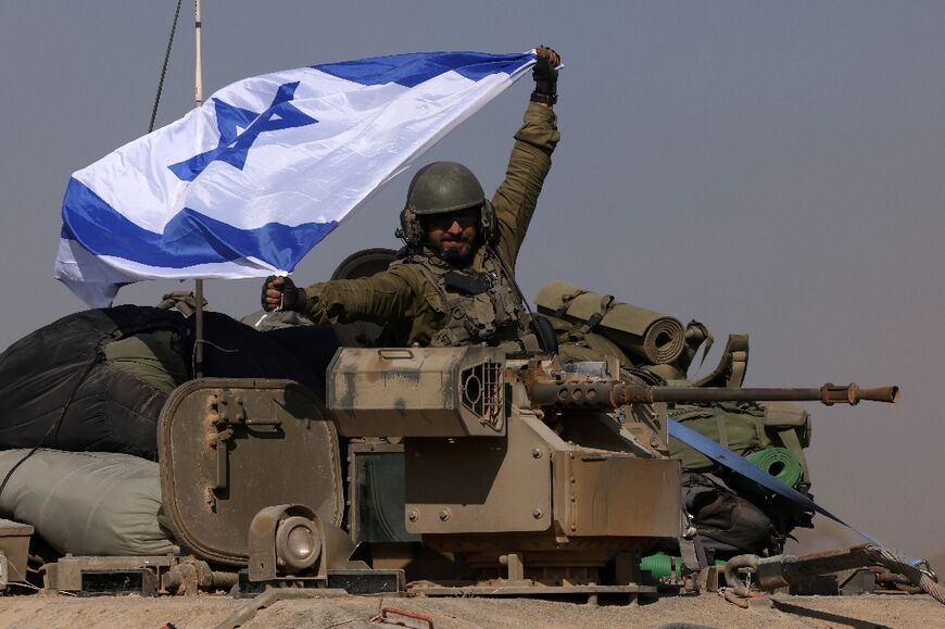 An Israeli soldier on an armoured personnel carrier waves an Israeli flag on December 31, 2023 amid continuing battles between Israel and Hamas