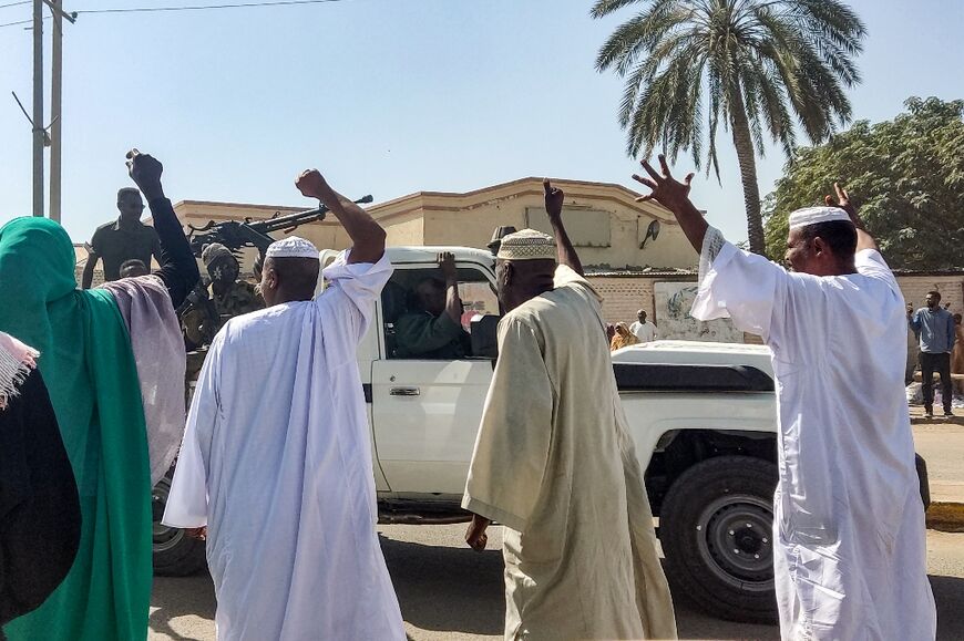 People displaced by the conflict in Sudan cheer as a Sudanese army truck driving by in the city of Gedaref