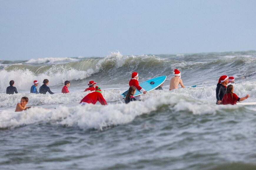 Surfers ride waves during the 15th annual 'Surfing Santas' event in Cocoa Beach, Florida