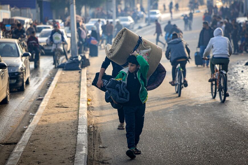 Palestinians carry their belongings as they seek safer areas following the resumption of Israeli strikes on the Gaza Strip