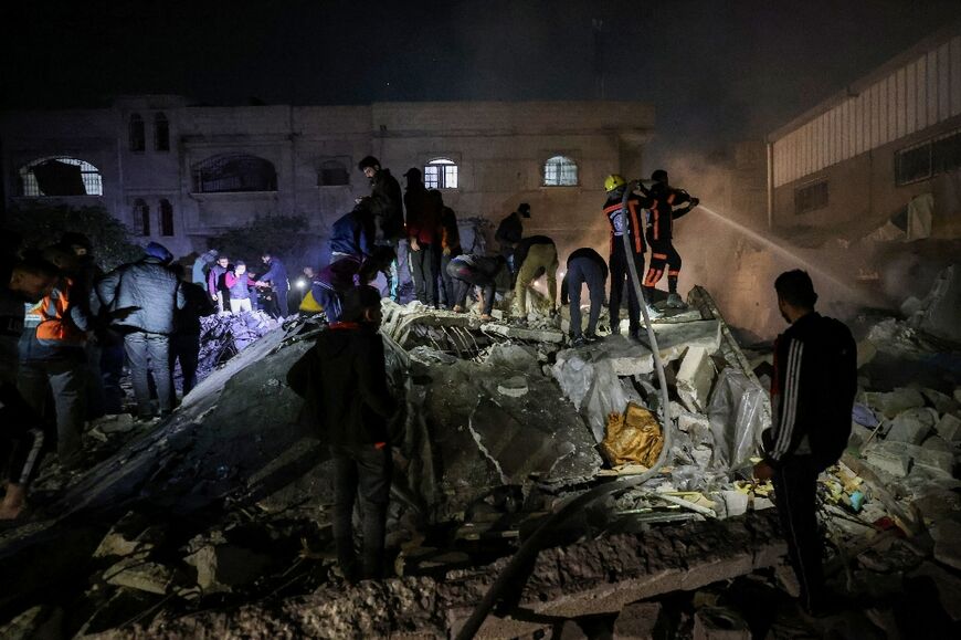 Firefighters and civilians gather at the rubble of a building following Israeli bombardment in Rafah