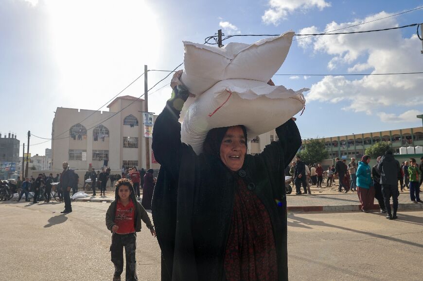 Palestinians receive bags of flour at the UNRWA distribution center in Rafah refugee camp, southern Gaza, during the Israel-Hamas war