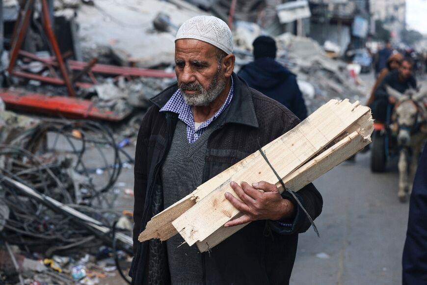A man carries firewood in Rafah in the southern Gaza Strip on January 14, 2024, as the ongoing war between Israel and the Palestinian militant group Hamas enters its 100th day