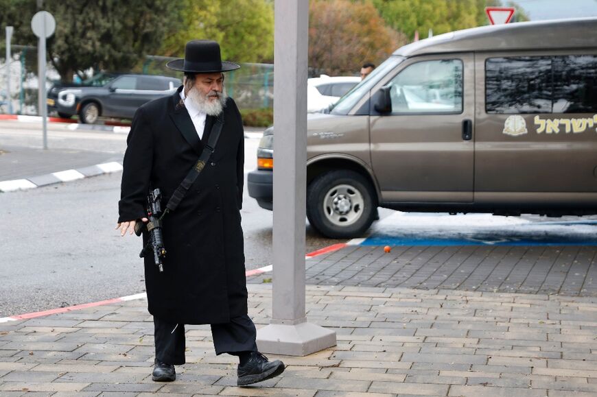 An ultra-Orthodox Jewish man carries a weapon as he arrives for the funeral of an Israeli mother and son killed after a missile fired from Lebanon hit a house in the border community of Kfar Yuval