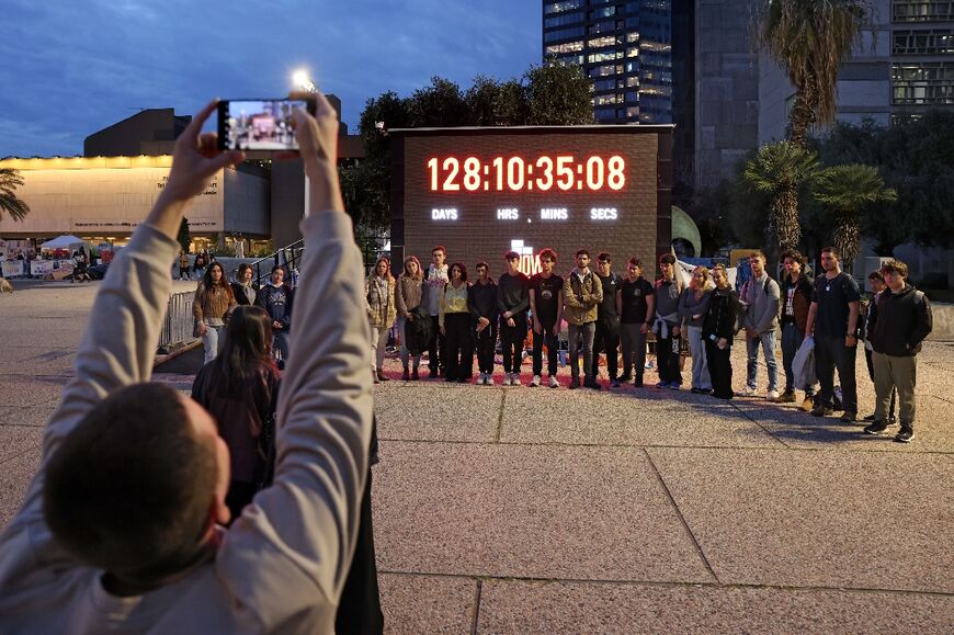 Relatives and supporters of hostages pose on February 12 in front of a screen showing the days, hours, minutes and seconds since the October 7 attack