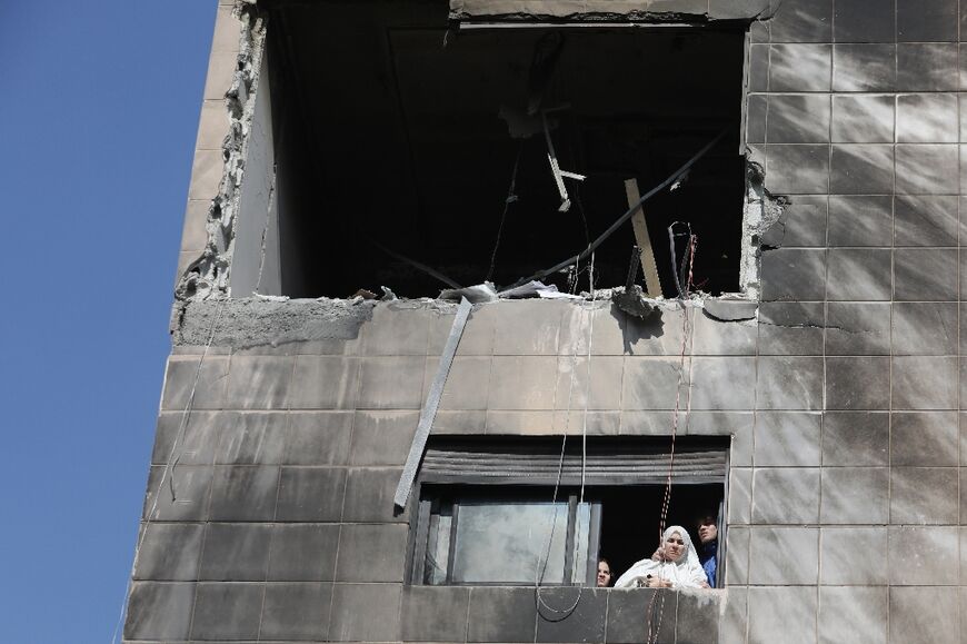 A woman and family members look out from the window of the building that was hit in the deadly strike 