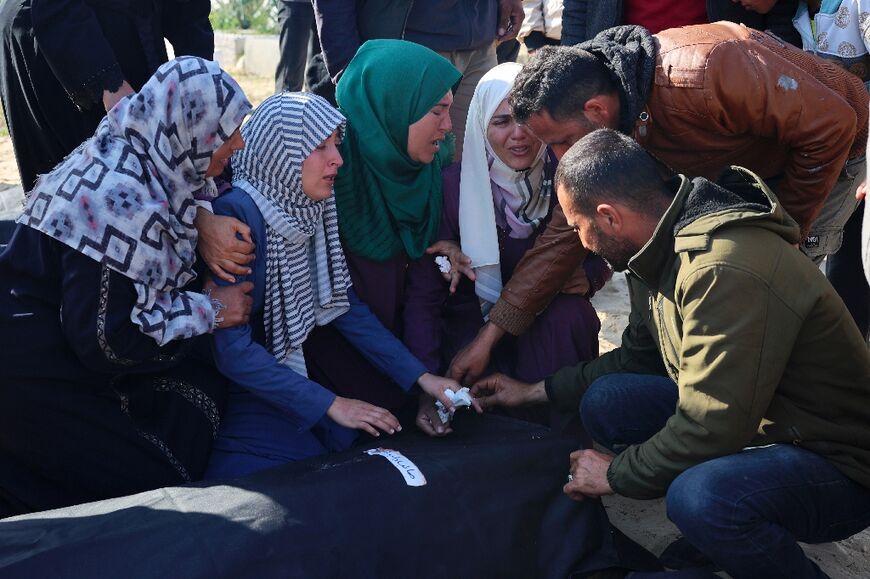 Relatives mourn over the body of a loved one killed during overnight Israeli strikes before his burial at a cemetery in Rafah, on the southern Gaza Strip on February 21, 2024