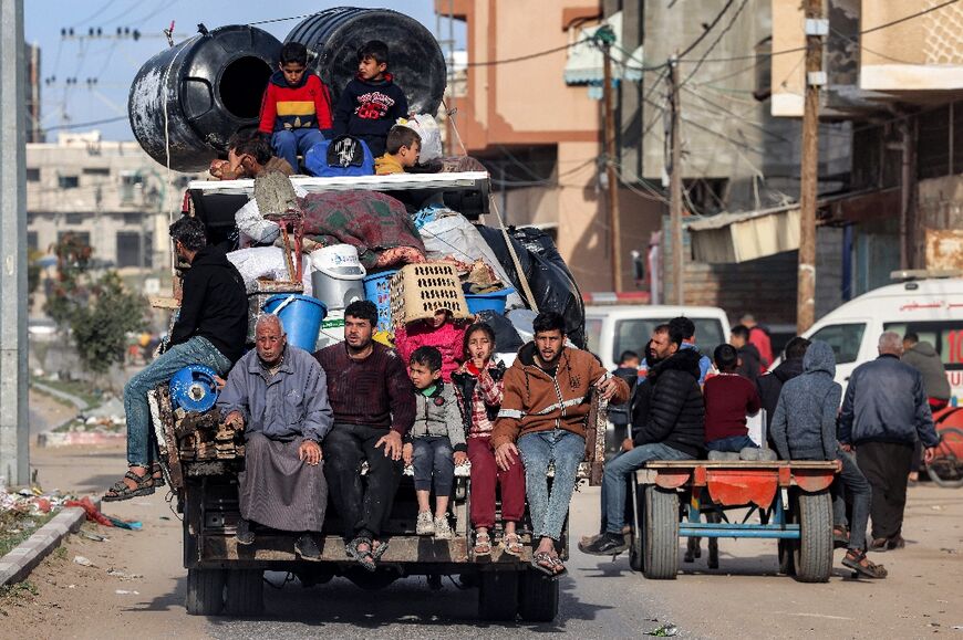Palestinians ride in the back of a truck with belongings as they flee Rafah towards central Gaza