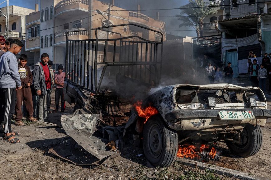 Members of the Palestinian Civil Defence extinguish a burning car following Israeli bombardment in Rafah