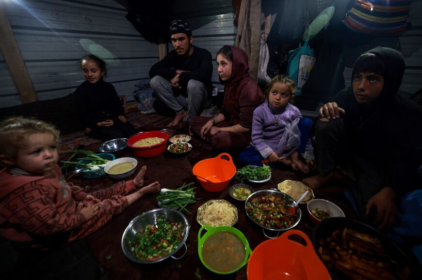 Palestinians prepare for an iftar meal on the second day of Ramadan, at a displacement camp in southern Gaza's Rafah