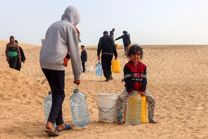 Palestinians transport water to a camp for displaced people in Rafah in the southern Gaza Strip on March 17, 2024