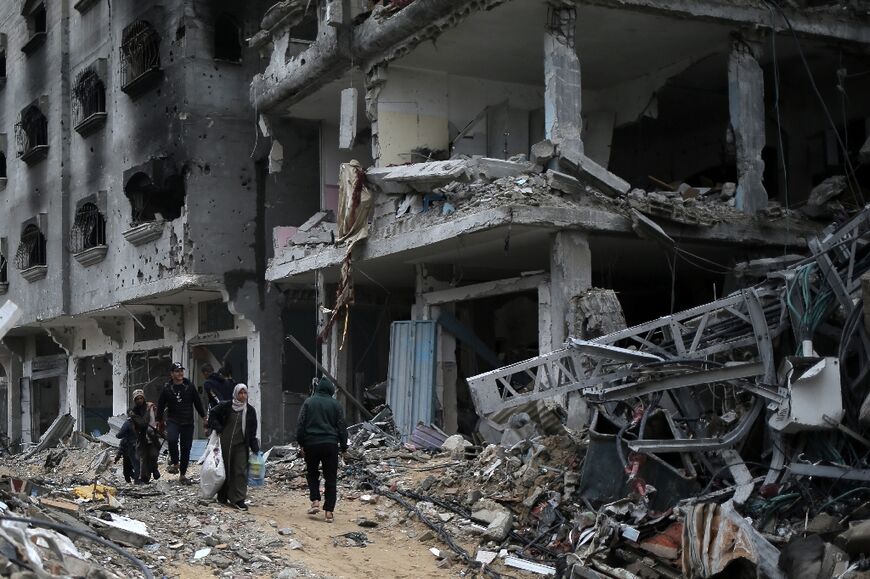 Palestinians walk past buildings gutted by Israeli bombing in the south Gaza city of Khan Yunis