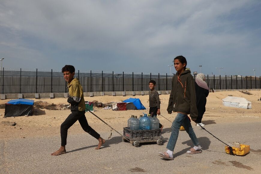 Children in Gaza's Rafah, where Israel has repeatedly threatened to invade, carry water to a displacement camp
