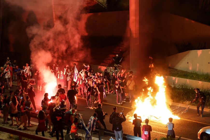 Israeli demonstrators in Jerusalem block a main road during a protest against their government and to demand a secure release of hostages held by Hamas militants in Gaza