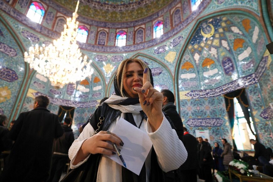 An Iranian woman shows her ink-stained finger after casting her ballot at a polling station in Tehran on March 1, 2024