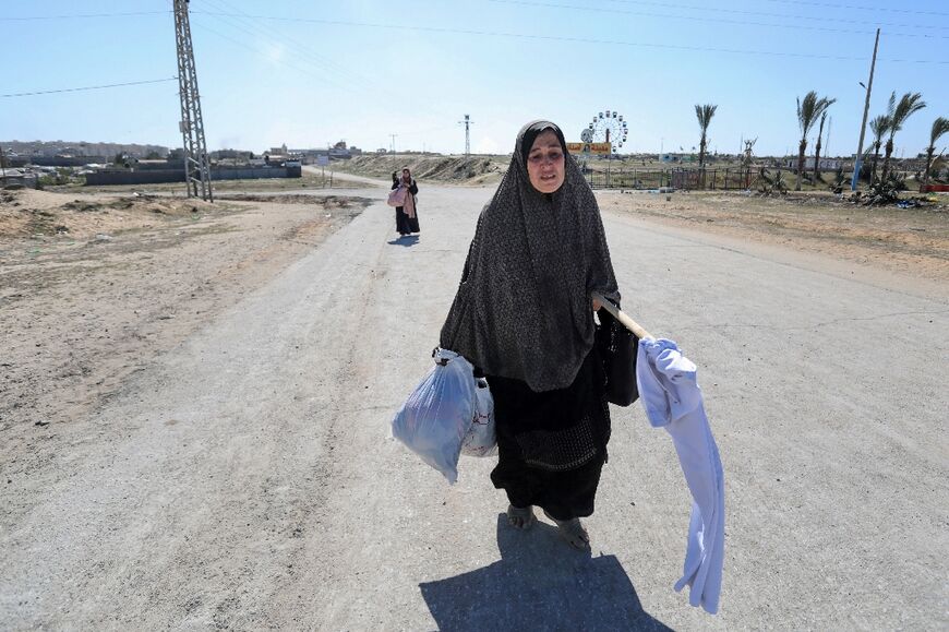 A displaced Palestinian woman carrying a makeshift white flag flees Hamad in Gaza, where Israel has conducted strikes
